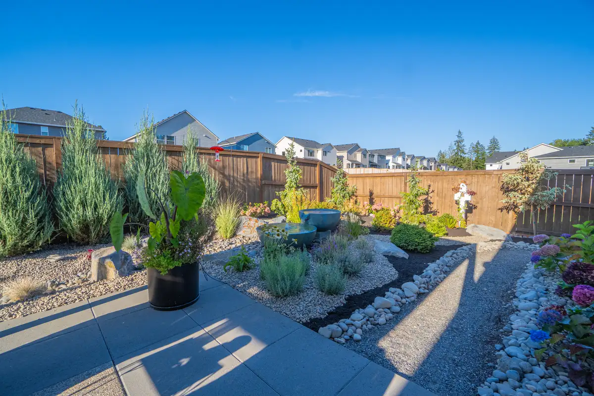 Backyard landscape design with pergola and river rock by CreekView Landscape