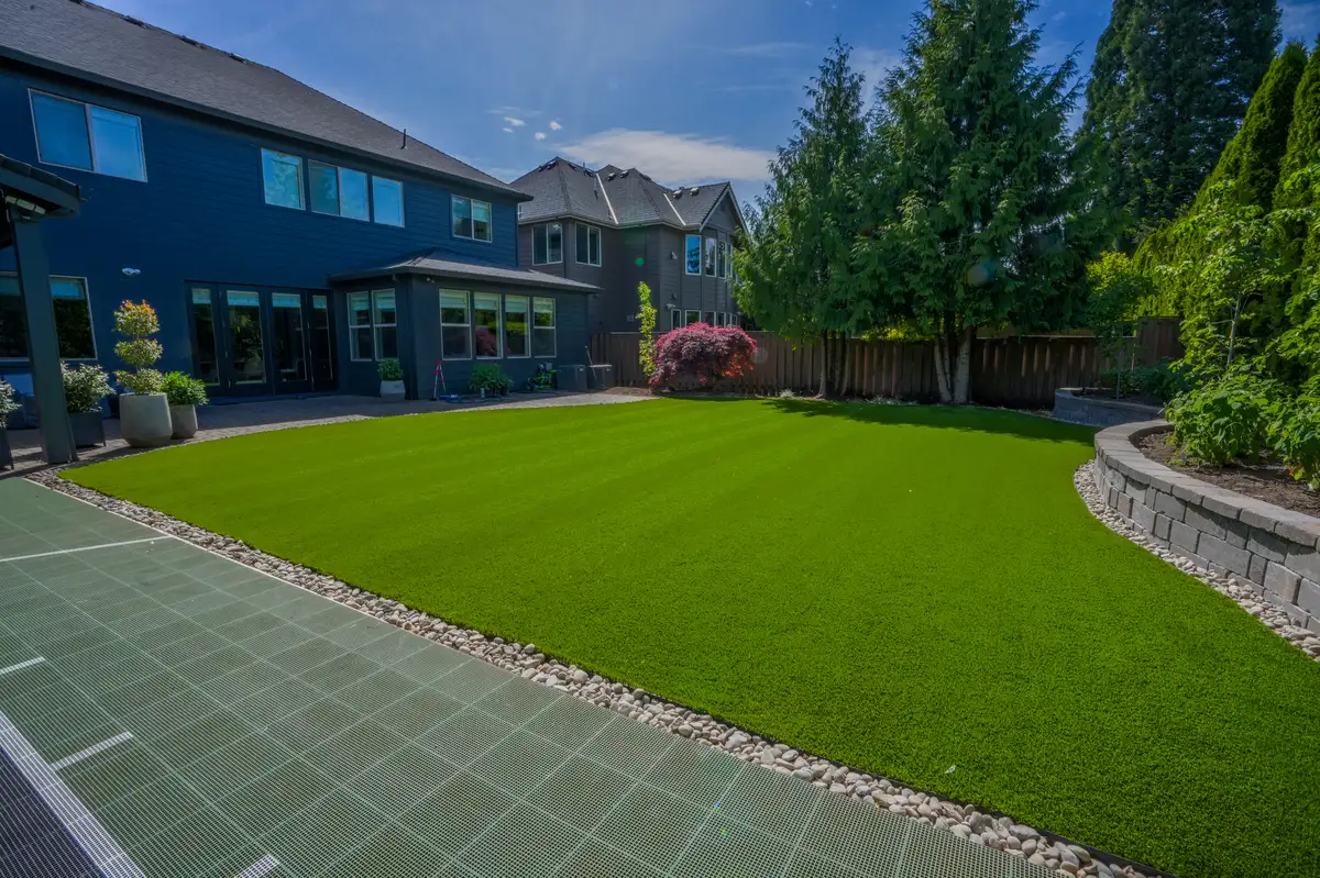 Luxury backyard with artificial turf paver patio and sport court by CreekView Landscape